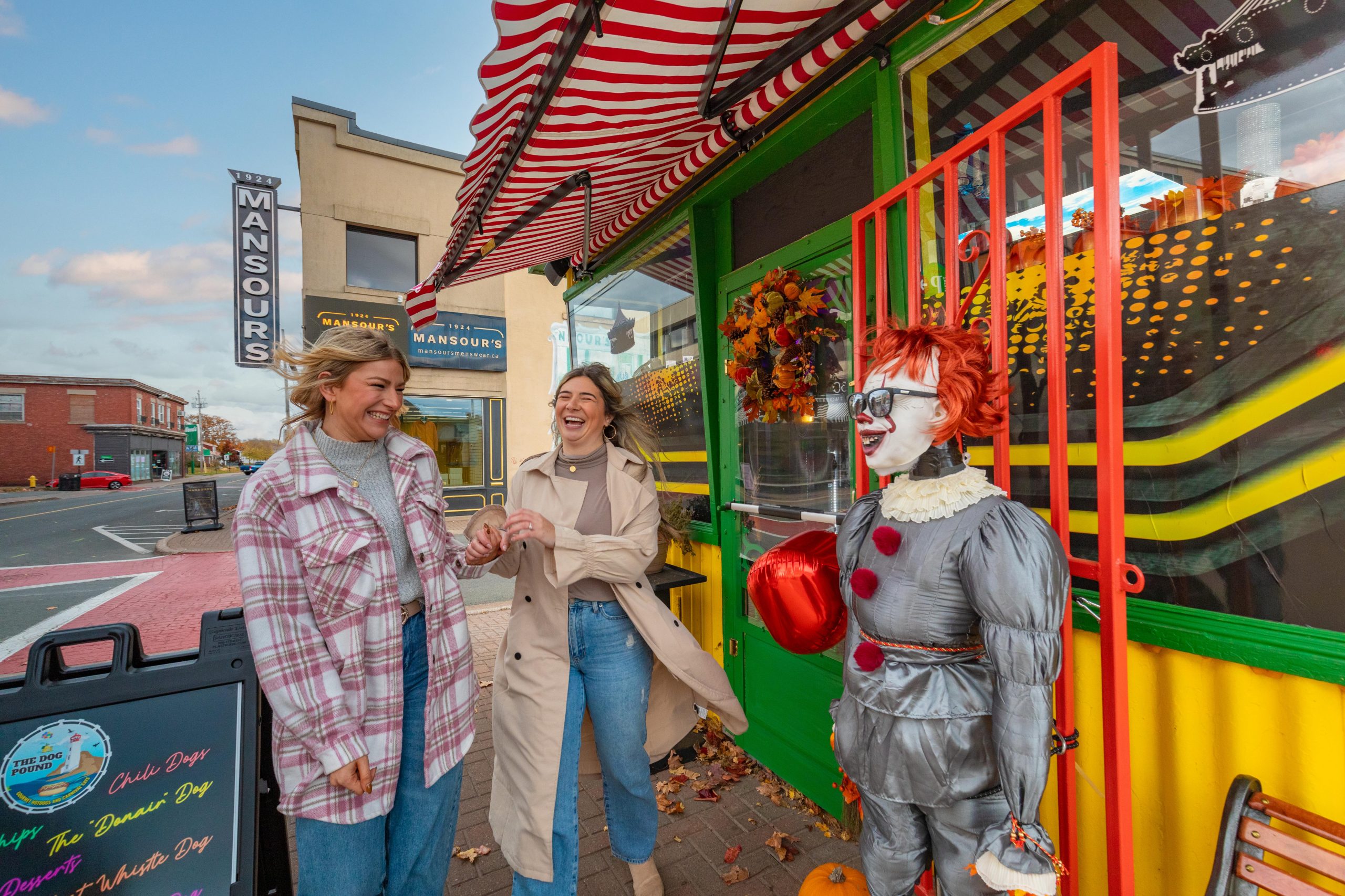 Two women laughing at at a scarecrow dressed as a clown