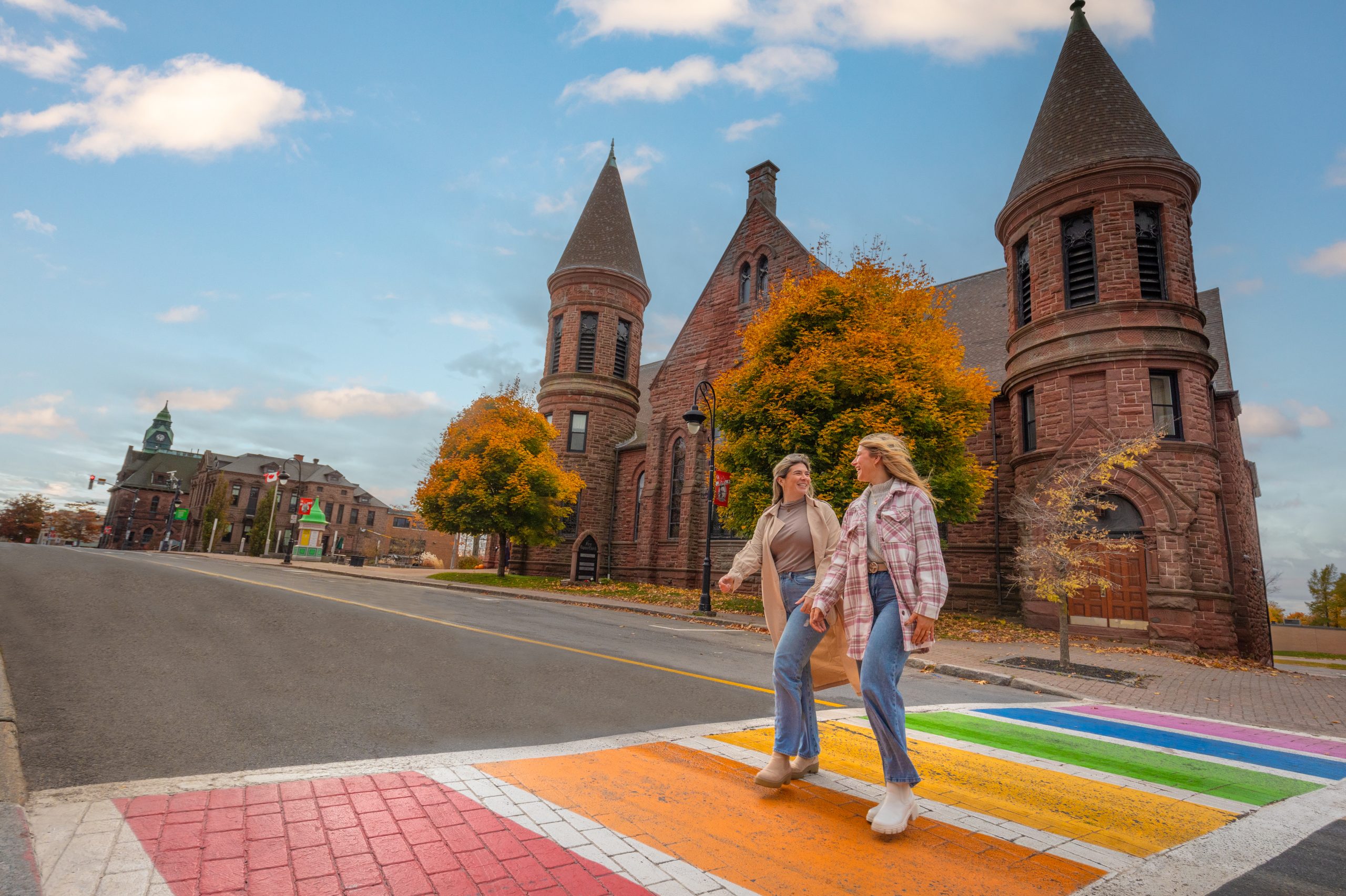 Two people walking across a rainbow crosswalk in Downtown Amherst, Nova Scotia